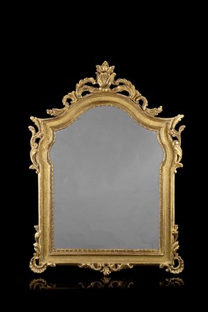 Specchiera in legno intagliato e dorato di forma mossa con cimasa traforata e...