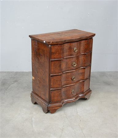 Comodino con fronte sagomato a quattro cassetti filettato in legno chiaro....