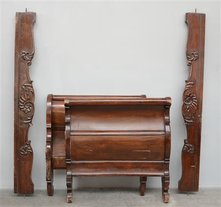 Letto a barca in noce con montanti intagliati a volute fogliate. Sec. XIX...