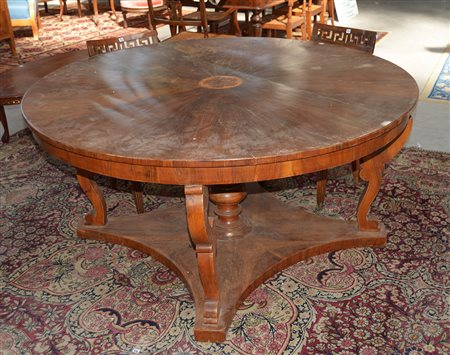 Tavolo in noce di forma tonda con montanti sagomati e gamba centrale a...