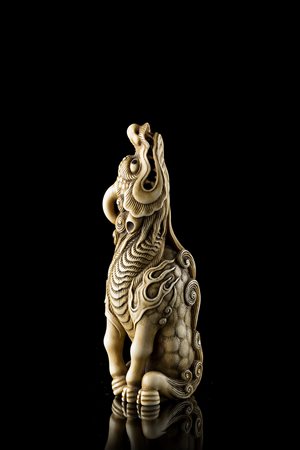 Netsuke in avorio raffigurante una kirin in posizione seduta, il muso rivolto...