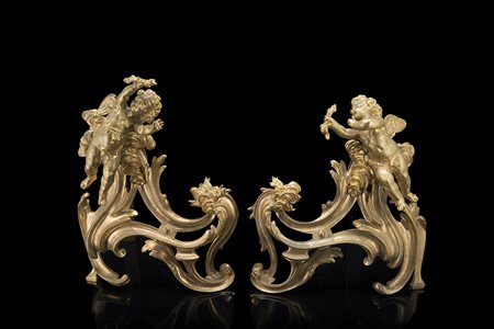 Coppia di alari in bronzo decorati a tutto tondo ad amorini, volute fogliate...
