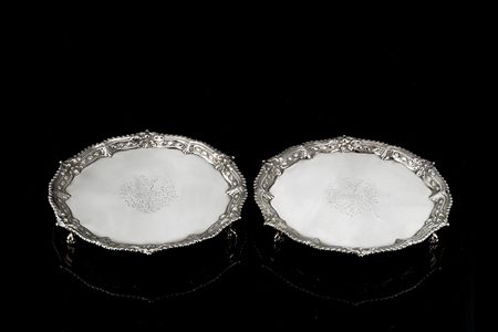 Coppia di salver in argento di forma circolare sagomata, con fondo liscio...