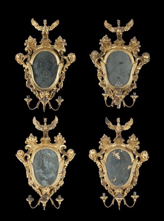 Gruppo di quattro appliques a tre luci in legno intagliato e dorato a teste...