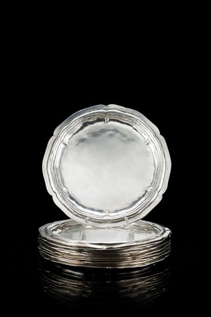 Otto piattini in argento di forma circolare sagomata con fondo liscio e tesa...