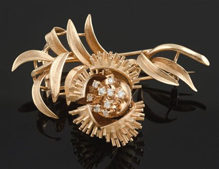 Spilla in oro rosa a forma di ramo con foglie satinate e lucide, al centro...