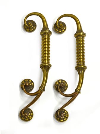 Coppia di maniglie in fusione di bronzo e ottone di gusto barocchetto....