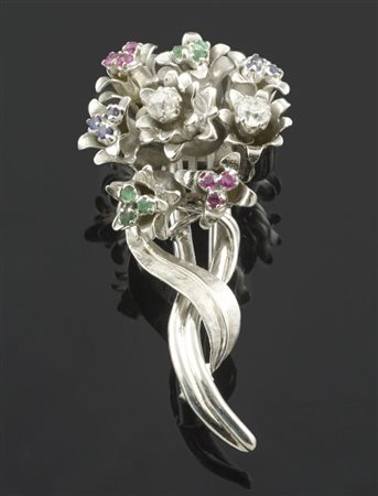 Spilla a forma di fiore in oro bianco con rubini, zaffiri e smeraldi. gr. 19,2.