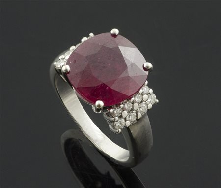 Anello in oro bianco con rubino centrale e 4 file di brillanti ai lati. gr. 8,2.