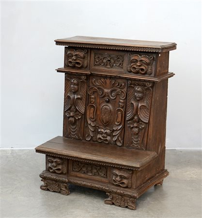 Inginocchiatoio in noce con fronte scolpito con grottesche, motivi vegetali e...