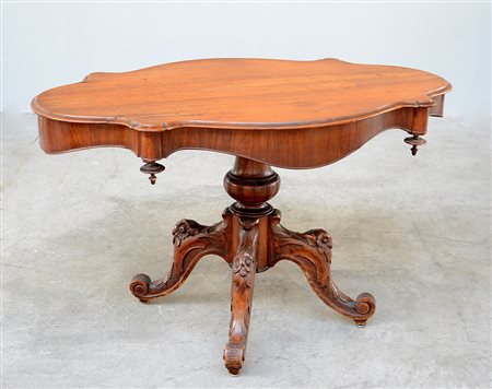 Tavolo a "biscotto" in noce con quattro gambe intagliate a decori floreali;...