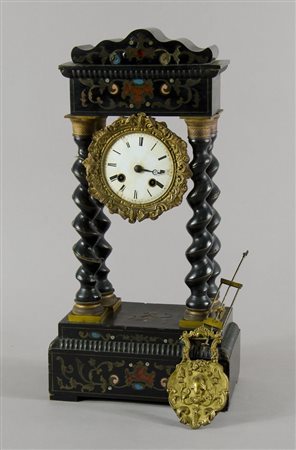 Orologio da tavolo in legno scuro su colonnete, decorato a lavorazione...