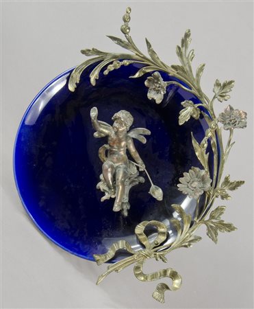 Piatto in ceramica blu con applicazioni floreali in metallo. Diam. Cm. 35.