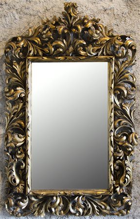 Grande specchiera con cornice in legno dorato riccamente scolpita a volute....