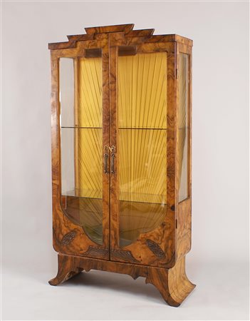 Vetrina Decò in noce di linea sagomata, fronte a due ante in cristallo molato...