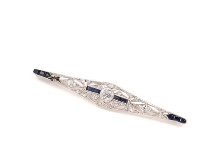 Spilla Decò in platino con incastonato al centro un diamante taglio brillante...