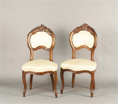 Quattro sedie in noce intagliato, schienali e sedute imbottiti e rivestiti in...