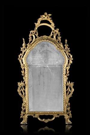 Specchiera di forma sagomata in legno intagliato, dorato e traforato a...