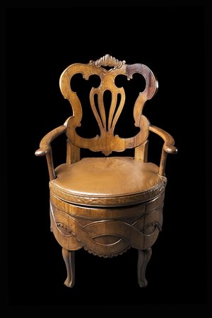 Poltrona-comoda in noce con schienale traforato e sagomato, braccioli e gambe...