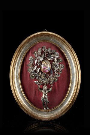 Fregio in argento, con putto alato a tutto tondo che sorregge uovo in...