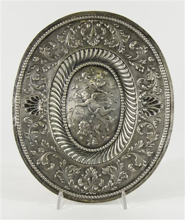 Piatto ovale in argento sbalzato a motivi floreali e figura di putto al...