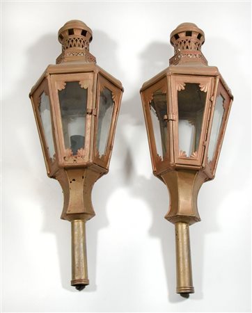 Coppia di fanali in ferro dipinto rosso, su pali in legno dipinto.