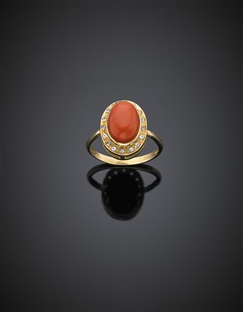 Anello in oro giallo con pietre incolori a contornare un corallo ovale...