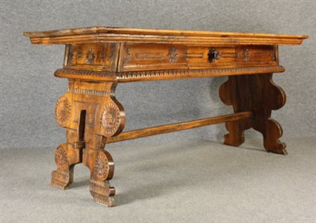 Firmato. Tavolo in legno di noce intagliato con cassetto, sul piano due busti...