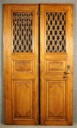 Firmato, datato. Coppia di porte in legno di noce pannellate e traforate....