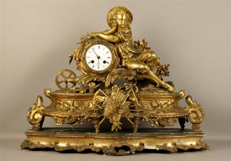 Firmato. Orologio da tavolo in metallo dorato raff. ''GIOVANE SEDUTO SULLA...