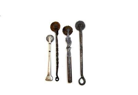 Lotto di quattro rondelle da pasta in ferro forgiate con manici con ricciolo...