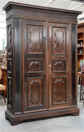 Armadio in pioppo a tinta scura con sportelli e fianchi bugnati, anta interna...