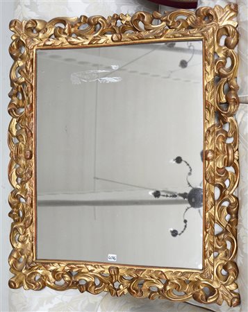 Cornice in legno intagliato, traforato e dorato a motivi vegetali e volute....