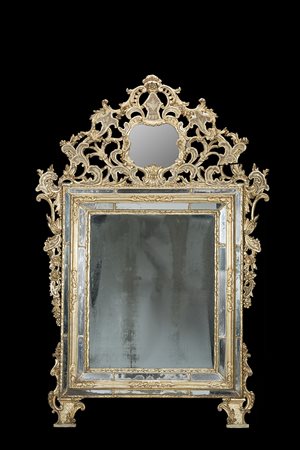 Specchiera in legno intagliato e dorato a mecca. Decorata a volute e motivi...