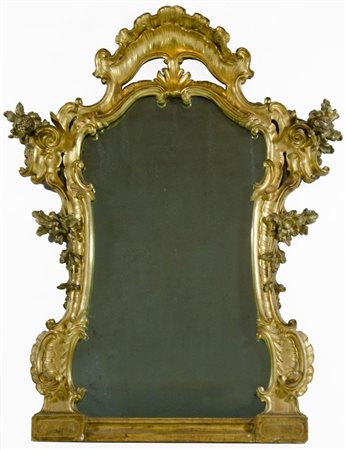 Grande specchiera sagomata in legno dorato decorata con intagli a motivi...