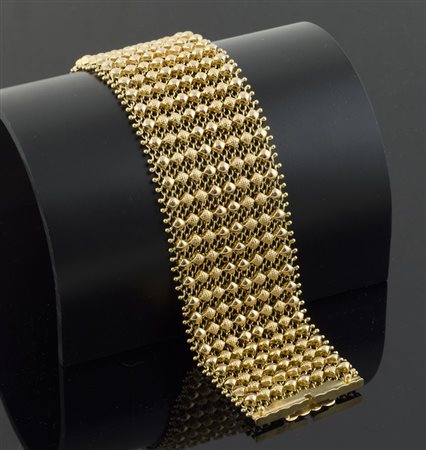 Bracciale a larga fascia in oro giallo lavorato a maglie traforate. Gr. 62,1.