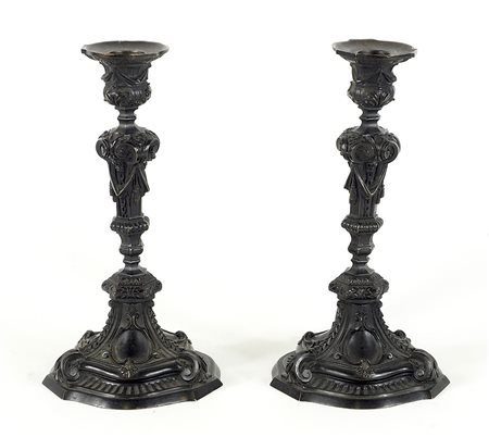 Paio di candelieri in bronzo a patina scura riccamente lavorati a sbalzo. H....
