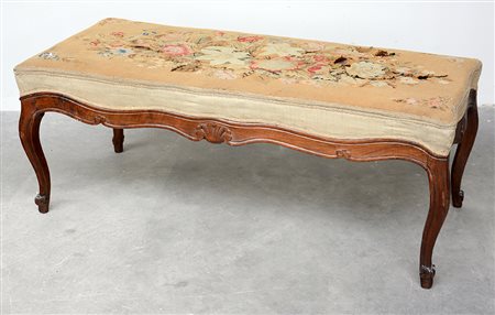 Panchetta di forma sagomata in noce intagliata a motivi vegetali, gambe...