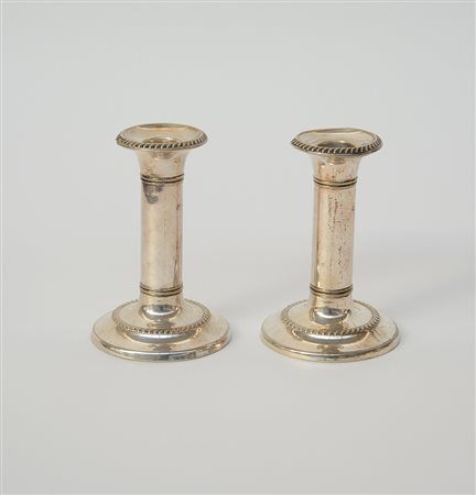 Coppie di candelieri a colonna in metallo argentato con ghiere decorate...