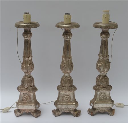 Gruppo di tre antichi candelieri tripodi in legno intagliato e dorato a...