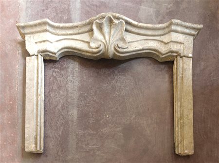 Antico camino in marmo grigio con architrave sagomata e decorata al centro...