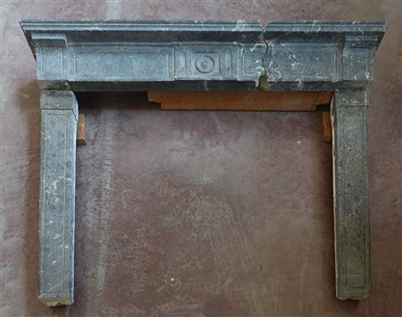 Camino in marmo grigio con montanti ed architrave decorati con scanalature...