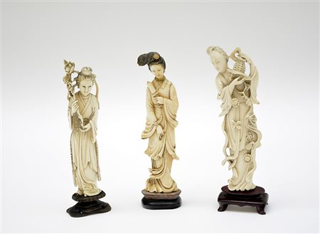 Tre sculture in avorio raffiguranti dame dalle lunghe vesti con basi in legno...