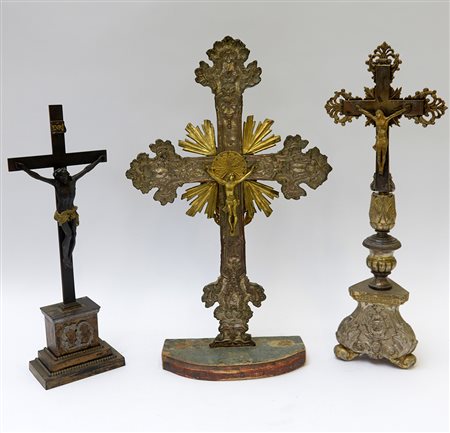 Lotto composto da tre crocifissi in legno, metallo e bronzo di epoche...