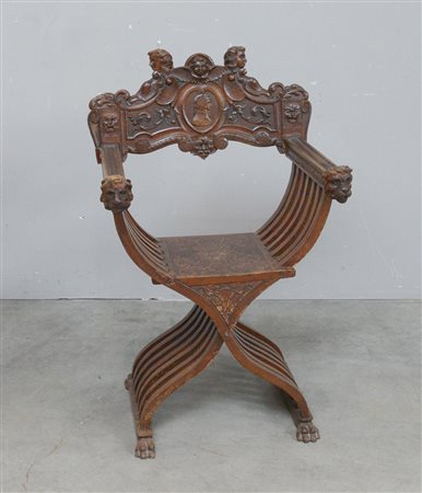 Poltrona "savonarola" con schienale decorato da profili e centrato da effige...