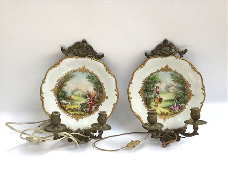 Coppia di applique in bronzo a due luci centrate da piatti in porcellana...