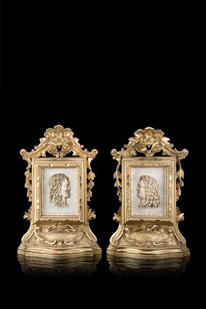 Coppia di teche in legno intagliato e dorato a volute e pendenti di foglie...