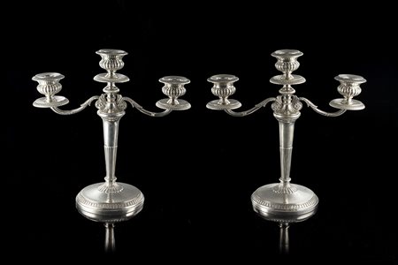 Coppia di candelieri in argento a tre fiamme con reggicandele decorati a...