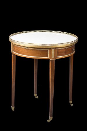 Tavolino di forma circolare lastronato in mogano a due cassetti e due tiretti...