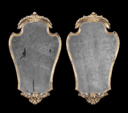 Coppia di specchiere sagomate in legno intagliato e dorato, decorate a motivi...